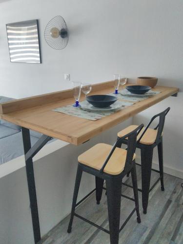 - une table en bois avec 2 chaises et des verres à vin dans l'établissement Studio Deauville-Les Marinas,vue mer et bassin, à Deauville