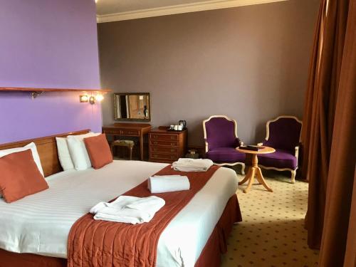 a hotel room with a bed and two purple chairs at Purbeck House Hotel & Louisa Lodge in Swanage