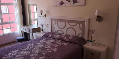 プラヤ・デ・サン・ファンにあるMarejada Apartment Tenerifeのベッドルーム1室(紫色のベッド1台、テーブル、窓付)