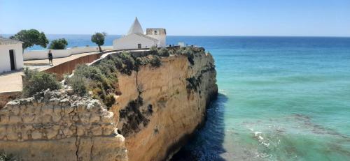 eine Kirche auf einer Klippe am Meer in der Unterkunft Amélia - Always Algarve in Armação de Pêra