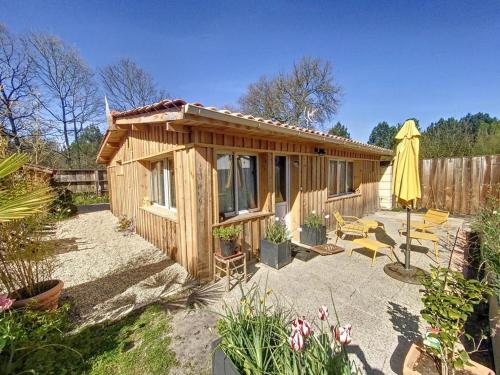 a small wooden cabin with a patio and an umbrella at le nichoir classé 3 étoiles maison 4pers climatisée 2pieces Audenge Bassin d'Arcachon in Audenge
