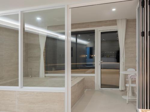 1 dormitorio y baño con puertas correderas de cristal. en White Castle Pension en Jeju