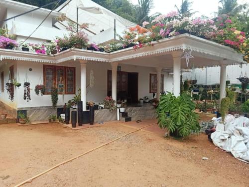 a white house with flowers on the roof at Moon moon Garden in Thamarassery