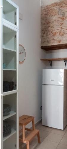 a kitchen with a white refrigerator and a wooden stool at LA RAJA in Scilla