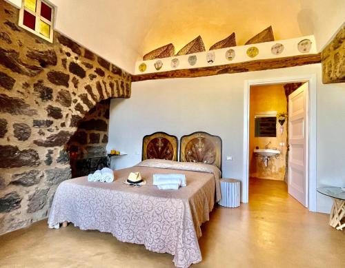 1 dormitorio con cama y pared de piedra en Dammuso Civulia, en Scauri