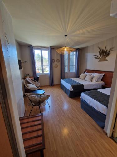 a hotel room with two beds and a table at Hotel Restaurant La Traverse in Cénac-et-Saint-Julien