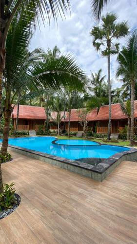 una piscina en un complejo con palmeras en Villa Lova Sambirenteng, en Gretek