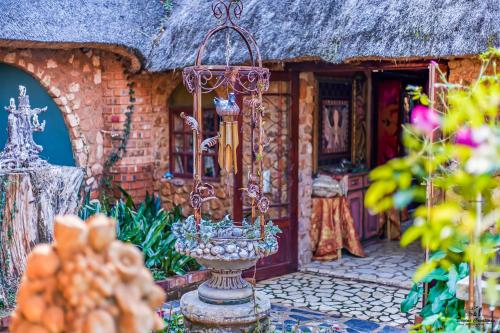 a house with a thatch roof with a vase in the yard at Duck and Dine in Pretoria