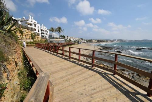 a wooden boardwalk leading to a beach with a building at Casa Oikos - La Cala de Mijas in La Cala de Mijas