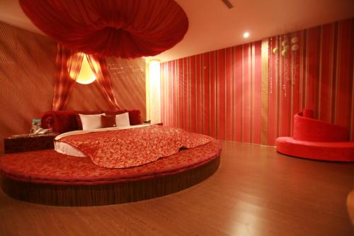 a bedroom with a bed in a room with red curtains at Vogue Boutique Motel in Yangmei