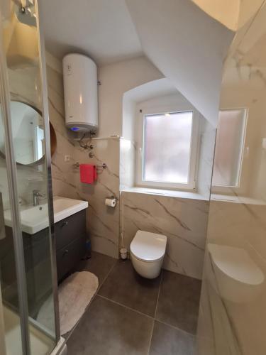 uma casa de banho com um WC, um lavatório e uma janela em Apartments Lana em Split