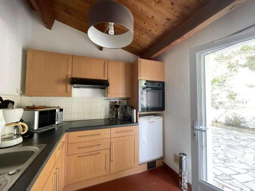 une cuisine avec des placards en bois et une grande fenêtre dans l'établissement Maison avec accès direct à la plage, 2 terrasses, jardin clos, 3 chambres, parking privé à La Guérinière - FR-1-224B-492, à La Guérinière