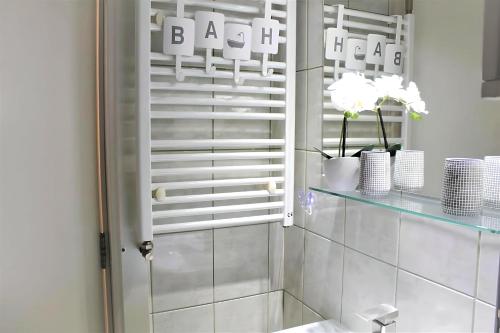 La salle de bains est pourvue d'une étagère en verre avec des tasses et des fleurs blanches. dans l'établissement Central Park View Sinaia, à Sinaia