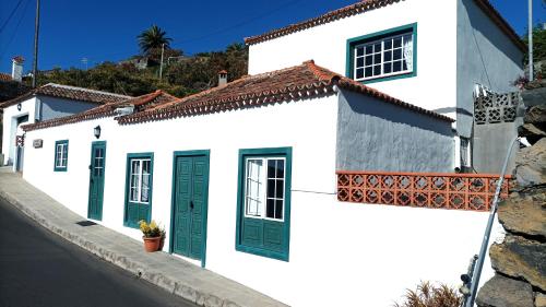 a white house with green doors on a street at La casa de Isabel in Mazo