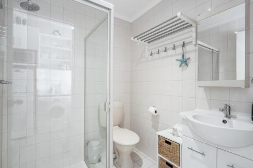 a white bathroom with a shower and a sink at Central and modern 2 bedroom unit at Smugglers in Victor Harbor