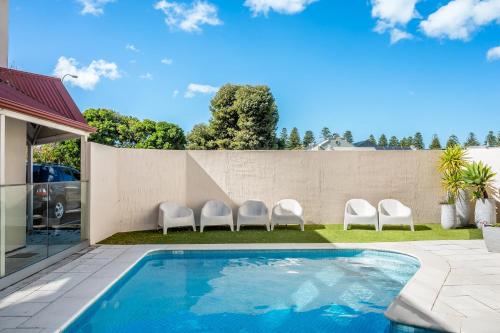 a backyard with a swimming pool with chairs and a fence at Central and modern 2 bedroom unit at Smugglers in Victor Harbor