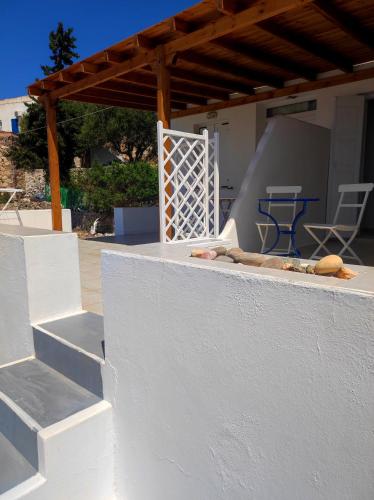 a white wall with a table and chairs on a patio at Georgia Rooms Milos in Plaka Milou