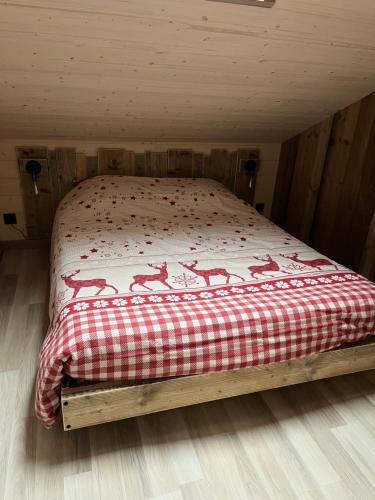 a bed with a red and white blanket on it at Chalet L'Ôbresse in La Bresse