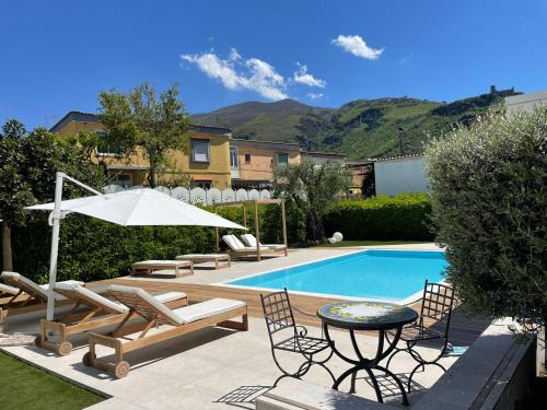 een zwembad met stoelen en een tafel en een parasol bij Home sweet Home in SantʼAntonio Abate