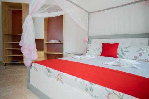 a bedroom with a large bed with a red pillow at The city Block Apartment in Bujumbura