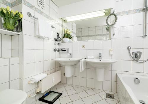 a white bathroom with two sinks and a mirror at Strandhotel Monbijou GmbH garni in Westerland (Sylt)