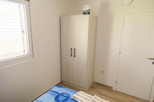 a white cabinet in a room with a window at Apartmani Marojević, Bar in Bar