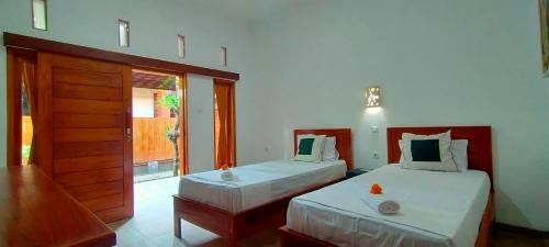 a bedroom with two beds and a door with a window at Tunjung guest house lovina beach in Buleleng