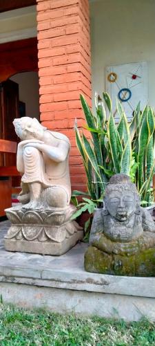 two statues sitting on the steps of a house at Tunjung guest house lovina beach in Buleleng