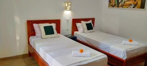 two beds in a hotel room with orange candles on them at Tunjung guest house lovina beach in Buleleng