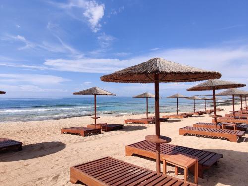 a beach with chairs and umbrellas and the ocean at Ayia Napa Villa with private pool in Ayia Napa