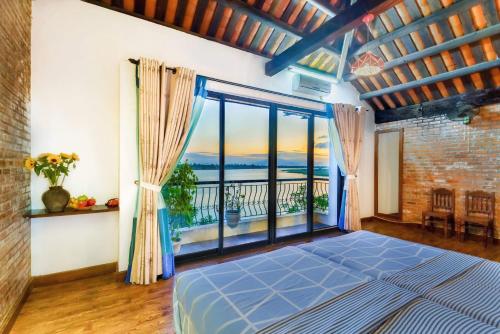 a bedroom with a bed and a large window at Calm House 2 HOSTEL in Hoi An