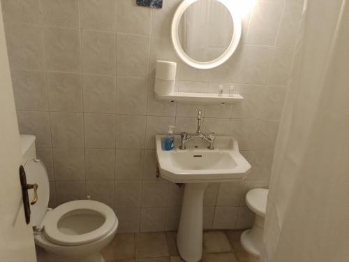 a bathroom with a sink and a toilet and a mirror at Miranta Hotel - Apartments & Studios in Aegina Town