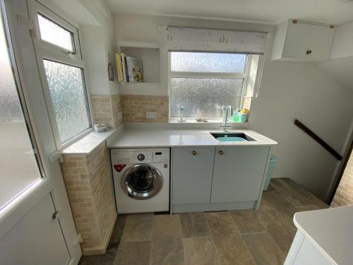 een keuken met een wasmachine en een wastafel bij Royal Oak Cottage in Amlwch