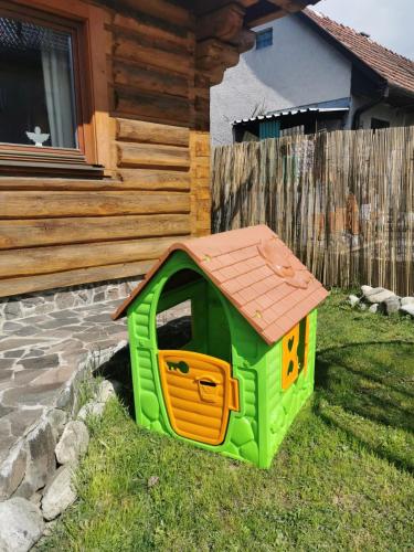 a green dog house in the grass in front of a house at Drevenica Západné Tatry s kúpacou kaďou a krbom in Žiar