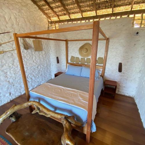 a bedroom with a canopy bed in a stone wall at Beach Bungalow-KiteAliCori , Macapa' in Luis Correia