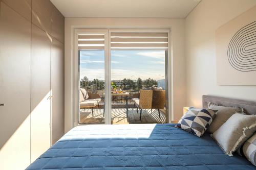 um quarto com uma cama azul e uma varanda em De Žavu home - Mano jūra 2 Kunigiškiai - by Hello Sea homes em Palanga