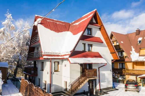 a house with a red roof in the snow at Willa Serce Gór in Zakopane