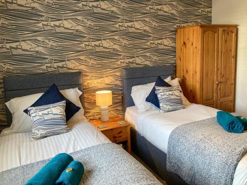 a bedroom with two beds and a wall with a wallpaper at The Boathouse in Appledore