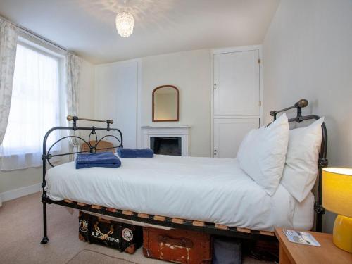 1 dormitorio con cama con sábanas blancas y chimenea en Tillerman Cottage appledore Devon, en Appledore