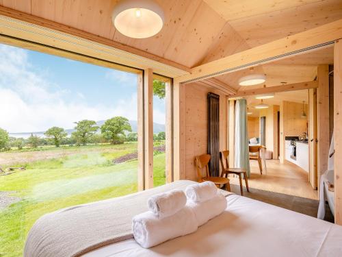 a bedroom with a bed and a large window at The Curve At Caerlaverock Estate in Glencaple