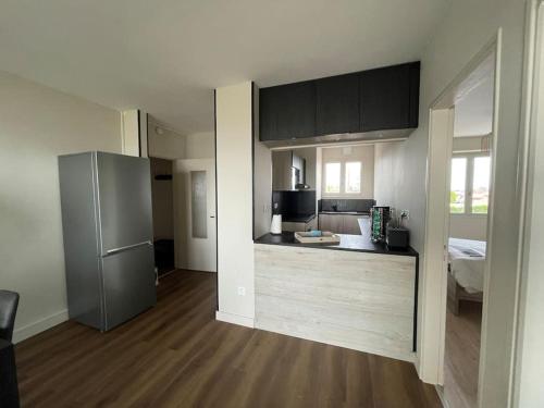 une cuisine avec des armoires noires et un réfrigérateur en acier inoxydable dans l'établissement Appartement vu mer, à La Faute-sur-Mer