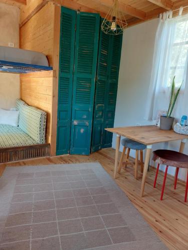 Cette chambre dispose de portes vertes, d'une table et d'un lit. dans l'établissement El Sheesh by Barefoot in Tunis, à Ibshawāy