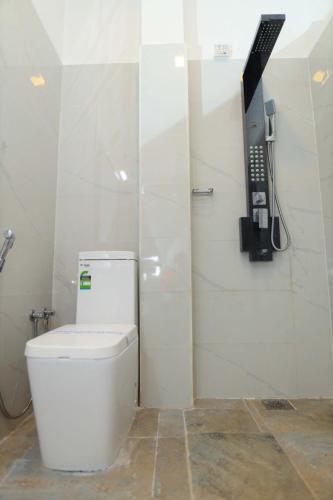a bathroom with a toilet and a phone on the wall at Blooming Holiday Resort in Anuradhapura
