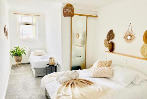 a white bedroom with two beds in it at Seafront Apartment in Portsmouth
