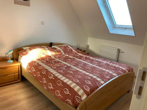 a bedroom with a bed with a red comforter and a window at Het Zonnetje Zonnebeke in Zonnebeke