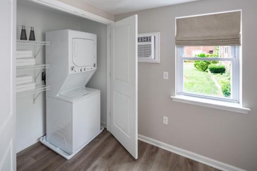 a white kitchen with a refrigerator and a window at Grazus ir modernus garazas prie Vilniaus centro in Vilnius