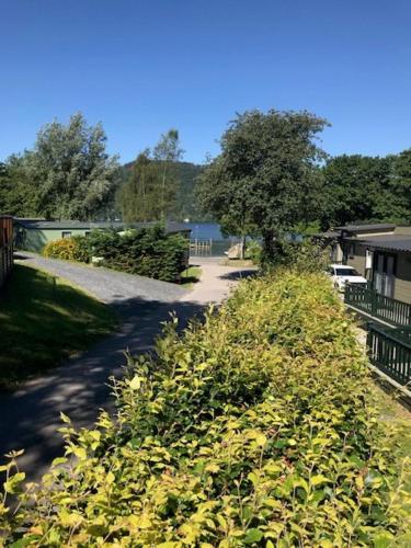 a path leading to a house with a bunch of plants at R11 Lake View, Fallbarrow Holiday Park in Bowness-on-Windermere