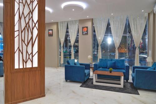 a lobby with blue chairs and a table and windows at سما الرفاع 3 in Al Kharj