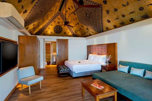 pokój hotelowy z łóżkiem i kanapą w obiekcie Outrigger Fiji Beach Resort w mieście Korotogo
