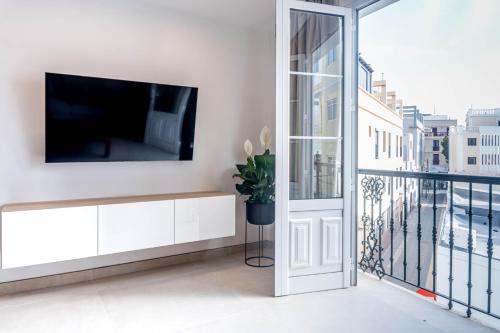 a living room with a tv on a wall next to a balcony at Rooms & Suites Loft 2F Deluxe Edition Arrecife in Arrecife